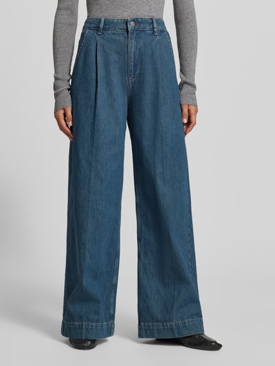 Frauenmodel trägt Wide Fit Jeans mit gelegten Falten von MYON, reine Baumwolle, mittelblauer Denim, Knopf- und Reißverschluss, Taschen, Nahaufnahme Unterkörper.