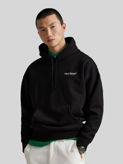 Männermodel trägt Relaxed Fit Hoodie aus katoenmix van Polo Ralph Lauren in effen kleuren met labelopschrift, kangoeroezak, capuchon met tunnelkoord, lange mouw en geribde details, sweatmateriaal; Nahaufnahme Oberkörper.