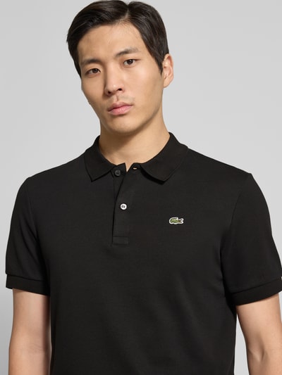 Männermodel trägt Regular Fit Poloshirt aus reiner Baumwolle von Lacoste, Optik: Unifarben, Logo-Detail, Nahaufnahme Oberkörper.