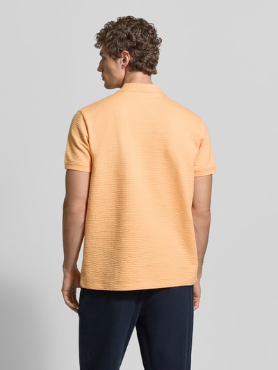 Männermodel trägt Regular Fit Poloshirt mit structuurpatroon van MCNEAL in perzik, katoenmix, ritssluiting, korte mouw, ruglengte maat M 70 cm, rugaanzicht.