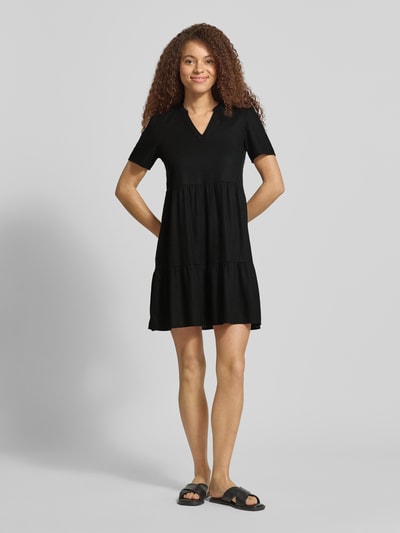 Vrouwenmodel draagt A-lijn vrijetijdsjurk van ONLY, model 'TIRI-GOA', look: effen zwart, mix van viscose en linnen, minilengte, V-hals, korte mouw, gevlamd garen, volledig frontaal beeld, ganzekörperansicht van voren.