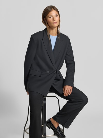 Frauenmodel trägt schwarzen Relaxed Fit Blazer mit Viskose-Anteil von MYON, doppelte Knopfleiste, elastisches Material, Ganzkörperansicht von vorne.