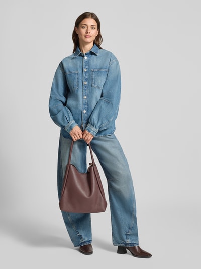 Frauenmodel trägt Handtasche aus echtem Leder Modell 'WILLOW' von Abro, dunkelbraun, glatte Struktur, Ganzkörperansicht von vorne. Szerokość w rozmiarze 30 cm, długość w rozmiarze 35 cm, głębokość w rozmiarze 15 cm, długość paska 52 cm, kieszenie wewnętrzne, logo marki, zamknięcie na magnes, wąskie ramiączka.