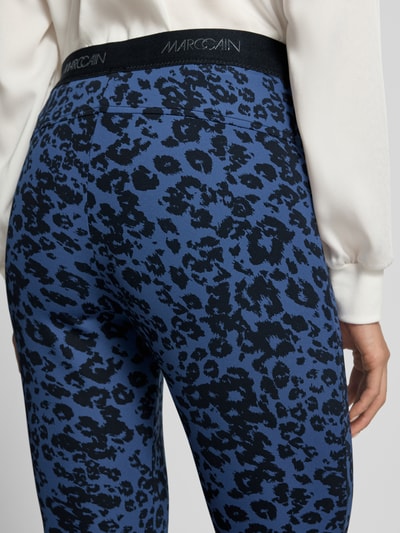 Frauenmodel trägt Flared Fit Leggings mit Allover-Animal-Print von Marc Cain in Blau und Schwarz, elastischer Bund, Detailaufnahme Rückenansicht.