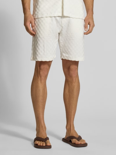 Männermodel trägt Regular Fit Shorts mit Label-Patch von Lindbergh, Baumwoll-Mix, weiß mit Strukturmuster, Ganzkörperansicht von vorne.