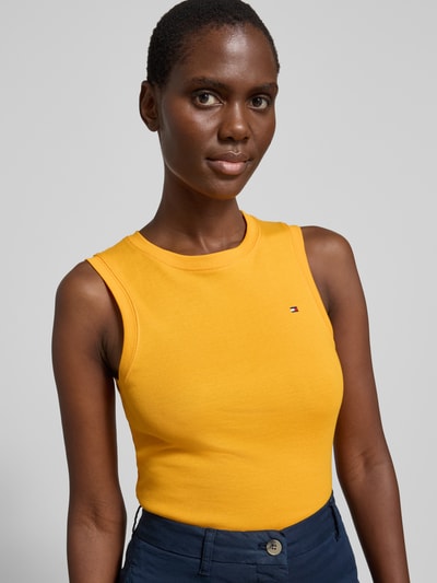 Frauenmodel trägt Slim Fit Tank Top aus reiner Baumwolle Modell 'SLIM CODY' von Tommy Hilfiger, unifarben gelb, Nahaufnahme Oberkörper.