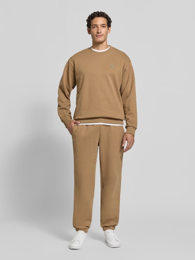 Männermodel trägt Regular Fit Sweatshirt aus Baumwoll-Mix von Lacoste in Beige, glatte Textur, Ganzkörperansicht von vorne. Herren Sweatshirt von Lacoste