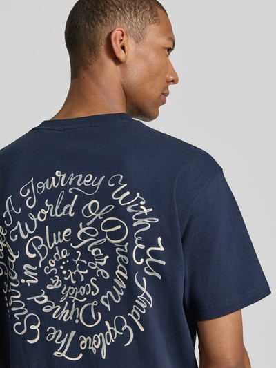 Männermodel trägt Oversized T-Shirt mit Logo-Stitching von Scotch & Soda in Dunkelblau, reine Baumwolle, Rückenansicht, Nahaufnahme Oberkörper.