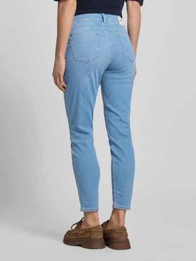 Kobieta nosi Slim Fit Jeans mit Eingrifftaschen Modell 'SHAKIRA' von Brax, mieszanka bawełny i lyocellu, jasnoniebieska, krój slim fit, wpuszczane kieszenie, szerokość w rozmiarze 36: 37 cm, długość wewnętrzna nogawki w rozmiarze 36: 70 cm, widok całej sylwetki z tyłu.