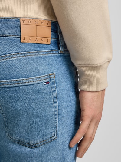 Männermodel trägt Slim Fit Jeans aus Baumwoll-Mix Modell 'SCANTON SLIM' von Tommy Jeans, Denim-Optik, Label-Patch, Detailaufnahme.