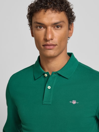 Männermodel trägt Regular Fit Poloshirt mit Label-Stitching von Gant in Grün, Reine Baumwolle, Polokragen, Knopfleiste, Nahaufnahme Oberkörper.