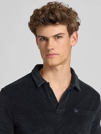 Männermodel trägt Slim Fit Poloshirt aus Frottee von Superdry in Schwarz, reine Baumwolle, offene Leiste, Nahaufnahme Oberkörper