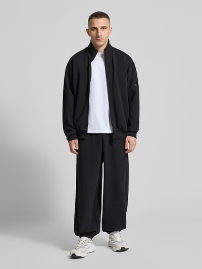 Männermodel trägt Comfort Fit Sweatpants mit Logo-Print von adidas Sportswear, Unifarben, Sweat, Ganzkörperansicht von vorne.