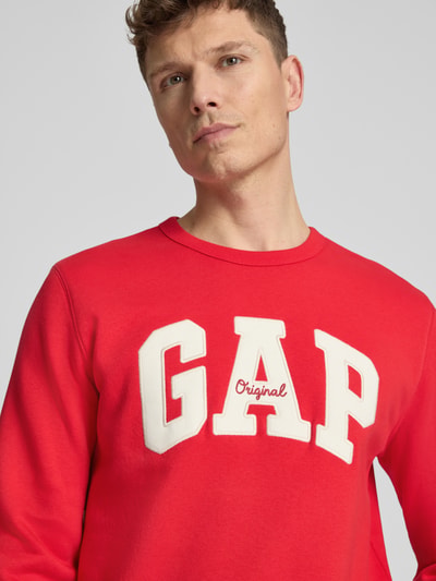 Männermodel trägt Sweatshirt mit Logo und Rundhalsausschnitt von GAP in Rot, aus Baumwoll-Mix, Regular-Fit, Logo, Nahaufnahme Oberkörper.
