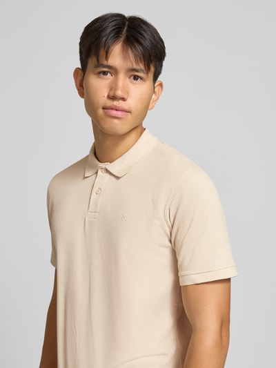Mężczyzna nosi Regular Fit Poloshirt mit Baumwoll-Anteil Modell 'Austin' od JACK & JONES, beżowy, strukturalny wzór, logo, krótkie rękawy, kołnierzyk polo, mieszanka elastyczna, widoczne boczne rozcięcia, szerokość w rozmiarze M: 68 cm, zbliżenie na górną część ciała.