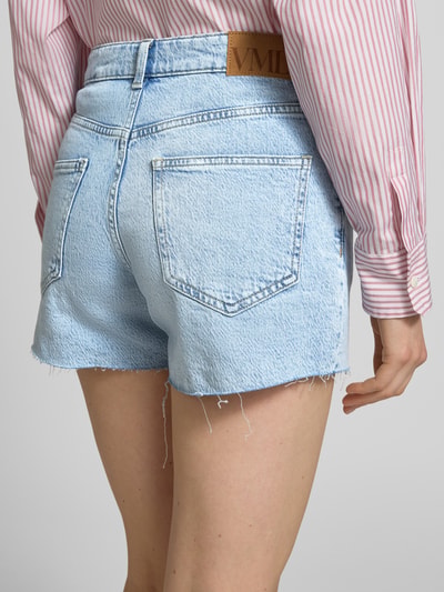 Vrouwenmodel draagt Regular Fit Shorts uit katoenmix model 'TESS' van Vero Moda, denimlook, labelpatch, 5-pocketmodel, kleur lichtblauw, mix van katoen, detailopname achteraan.
