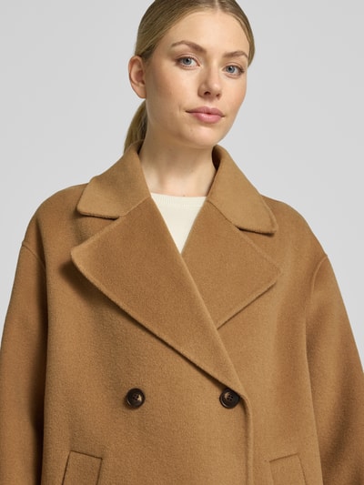 Modelka kobieca nosi Relaxed Fit Mantel aus reiner Wolle mit 2-Knopfleiste od Milano Italy w kolorze jasnobrązowym, tekstura wełny, kieszenie wpuszczane, długość tyłu 115 cm, szerokość ramion 45 cm, szerokość w rozmiarze 36: 56 cm, długość rękawa 55 cm, krój relaxed fit, widok z przodu, zbliżenie górnej części ciała.