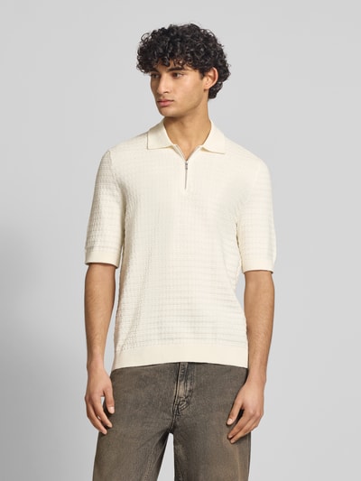 Männermodel trägt Regular Fit Poloshirt aus reiner Baumwolle Modell 'MENU' von Only & Sons in Flechtoptik, strukturierte cremefarbene Strickoberfläche, Polokragen, kurzer Reißverschluss, kurzarm, gerippte Abschlüsse; Ganzkörperansicht von vorne.