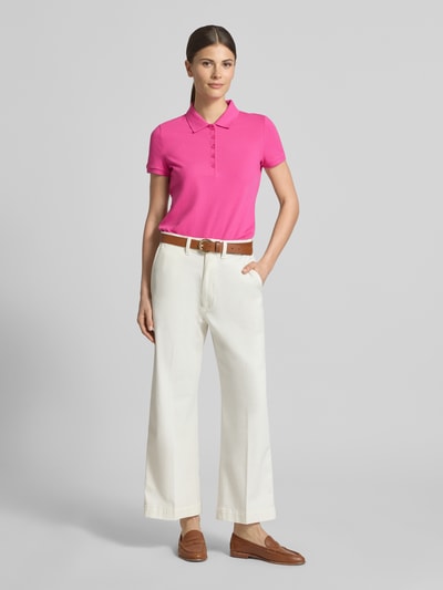 Frauenmodel trägt Slim Fit Poloshirt mit Knopfleiste von Christian Berg Woman aus Baumwoll-Elasthan-Mix in Pink, Seitenschlitze, Rückenlänge bei Größe S 62 cm, Ganzkörperansicht von vorne.