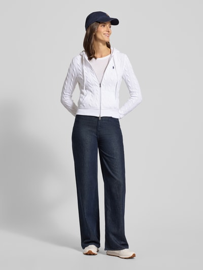 Kobiece modelka nosi Regular Fit Kardigan rozpinany z zamkiem błyskawicznym od Polo Ralph Lauren z bawełny, kaptur, tunel, haftowane logo, wpuszczane kieszenie, prążkowane wykończenia, kolor biały, całe ciało z przodu.