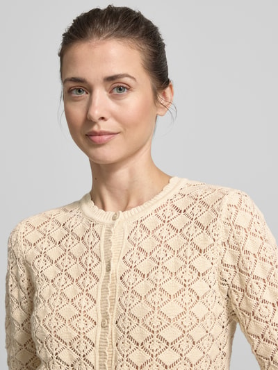 Frauenmodel trägt Regular Fit Strickjacke aus reiner Baumwolle Modell 'SOFIA' von Selected Femme, Optik: Unifarben, Ajour-Strick, Nahaufnahme Oberkörper.