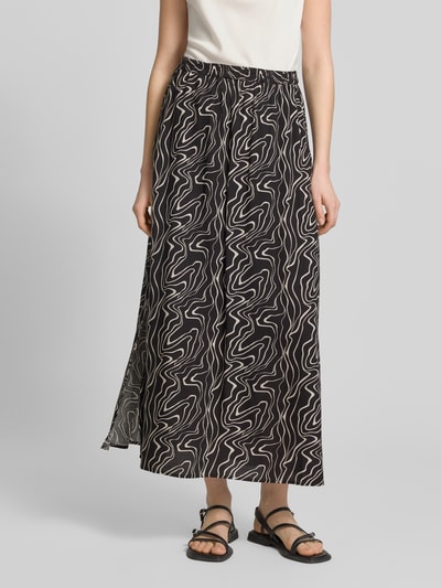 Frauenmodel trägt Ausgestellter Maxi-Rock aus reiner Viskose Modell 'EASY JOY' von Vero Moda mit grafischem Allover-Muster in Schwarz und Weiß, elastischer Bund, Popeline-Optik, Ganzkörperansicht von vorne.
