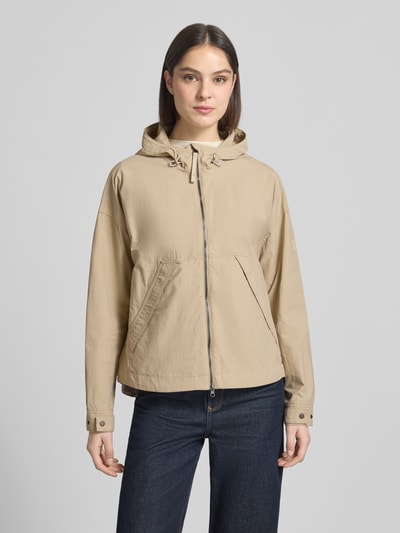 Frauenmodel trägt Jacke mit Kapuze und Zweiwege-Reißverschluss von camel active in Beige, Gerader-Schnitt, seitliche Eingrifftaschen, Verstellbare Ärmelabschlüsse, Rückenlänge 67 cm, Schulterbreite 44 cm, Brustweite 63 cm, Ärmellänge 62 cm, Ganzkörperansicht von vorne.