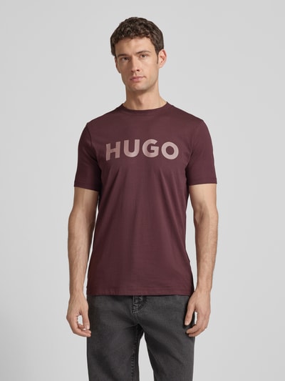 Männermodel trägt Regular Fit T-Shirt aus reiner Baumwolle Modell 'DULIVIO' von HUGO in Optik: Unifarben mit Label-Print, Rundhals, Kurzarm, Ganzkörperansicht von vorne.