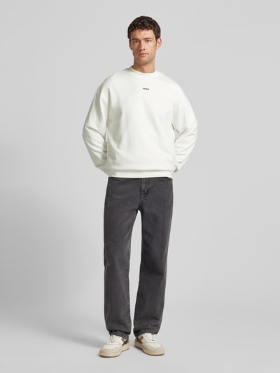 Männermodel trägt Regular Fit Sweatshirt aus reiner Baumwolle Modell 'DAPOCREW' von HUGO in Weiß, unifarben, langarm, Ganzkörperansicht von vorne.