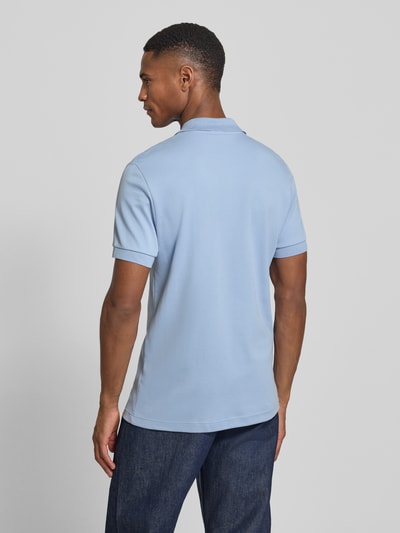 Männermodel trägt Regular Fit Poloshirt aus reiner Baumwolle von Lacoste in Hellblau, Logo-Detail, unifarben, Ganzkörperansicht Rückansicht.