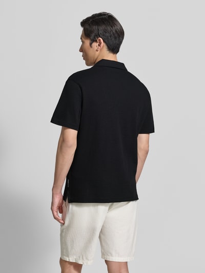 Männermodel trägt Relaxed Fit Poloshirt aus Baumwoll-Mix von Tom Tailor Denim in Schwarz, unifarben, Piqué-Struktur, Ganzkörperansicht Rückansicht.