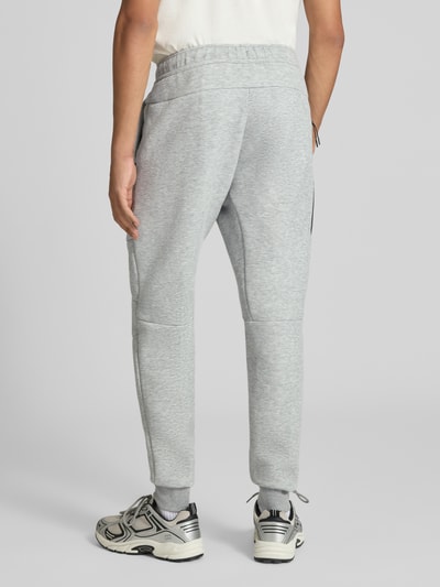 Männermodel trägt Slim Fit Sweathose aus Baumwoll-Mix von Nike in Hellgrau mit weicher Textur und schmalem Schnitt, Ganzkörperansicht Rückansicht. Herren Sweathose von Nike.