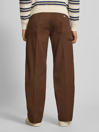 Männermodel trägt Loose Straight Fit Hose mit Bügelfalten von Dickies in Braun, Material-Mix mit Baumwoll-Anteil, Ganzkörperansicht Rückansicht.