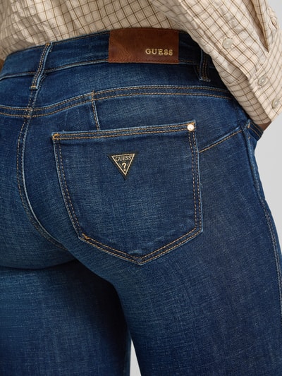 Vrouwenmodel draagt Slim Fit Jeans uit katoenmix Model 'Curve' van GUESS, donkerblauw, 5-pocketmodel, detailopname rugpartij.
