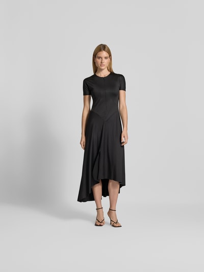 Frauenmodel trägt Midikleid mit verlängerter Rückseite von Victoria Beckham in Schwarz, elastischer Material-Mix, Regular Fit, Kurzarm, Frontreißverschluss, glatte Struktur, Ganzkörperansicht von vorne.