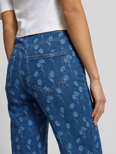 Frauenmodel trägt Wide Leg Jeans aus Baumwoll-Mix Modell 'TESSA' von Vero Moda, florales Allover-Muster, Denim-Struktur, Nahaufnahme Rückansicht.