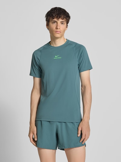 Männermodel trägt T-Shirt mit Logo-Print und Raglanärmeln von NIKE TRAINING in Türkis, Straight Fit, Rundhalsausschnitt, Ganzkörperansicht von vorne.