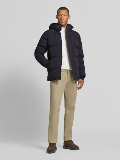 Männermodel trägt schwarze Regular Fit Steppjacke mit Reißverschlusstaschen Modell 'JAXHAM' von Cars Jeans, Material-Mix, Kapuze, Ganzkörperansicht von vorne.