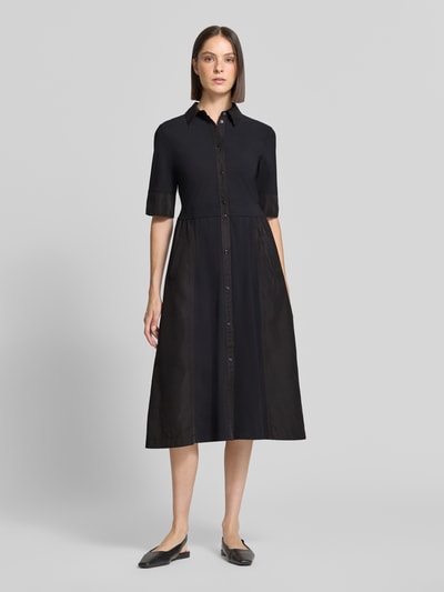 Vrouwenmodel draagt Midikleid met Umlegekragen van Marc Cain in zwart, elastische materiaalmix, getailleerde pasvorm, knoopsluiting, 1/2-mouwen, steekzakken, ruglengte maat 36: 120 cm, borstwijdte: 46 cm, mouwlengte: 32 cm, volledige frontale lichaamsweergave.