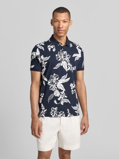 Mannenmodel draagt Modern Fit poloshirt met labeldetail van Lerros, donkerblauw met witte bloemenprint, puur katoen, polokraag, korte knoopsluiting, ruglengte bij maat M 74 cm, Ganzkörperansicht von vorne.