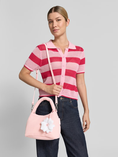 Frauenmodel trägt Shoulder Bag in Strick-Optik von Marc Cain in Rosa mit floralem Besatz, Breite 22 cm, Länge 16 cm, Tiefe 14 cm, Nahaufnahme Oberkörper.