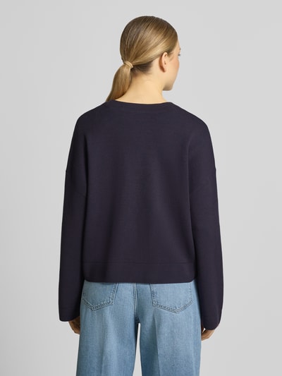 Frauenmodel trägt Strickjacke aus Viskose-Mix mit V-Ausschnitt von Comma in Dunkelblau, Relaxed-Fit, Knopfleiste, Rückenlänge 54 cm, Ärmellänge 47 cm, Damen Strickjacke, Ganzkörperansicht Rückansicht