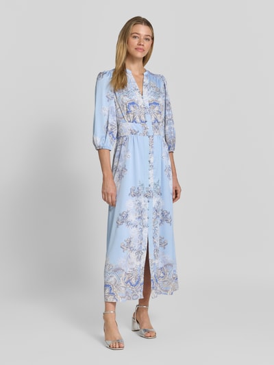 Frauenmodel trägt Maxikleid mit V-Ausschnitt und 3/4-Arm Modell 'Stellar Artist' von Neo Noir, Allover-Look, A-Linie, Knopfleiste, Ganzkörperansicht von vorne. Rückenlänge bei Größe 36: 131 cm, Brustweite: 41 cm, Ärmellänge: 49 cm.