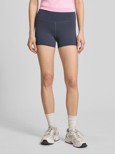 Frauenmodel trägt Slim Fit Shorts mit Logo-Print Modell 'Reflect' von P.E Nation aus Elastischer-Material-Mix, Dunkelblau, Ganzkörperansicht von vorne.