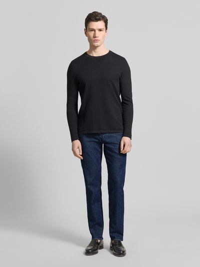 Männermodel trägt Sraight Fit Jeans mit Eingrifftaschen Modell 'Cadiz' von Brax, dunkelblauer Baumwoll-Elasthan-Mix, Used-Look, Ganzkörperansicht von vorne.