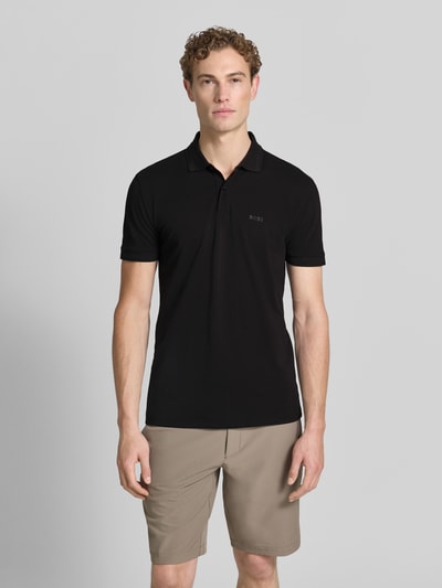 Männermodel trägt schwarzes Regular-Fit Poloshirt aus reiner Baumwolle Modell 'PIO 1' von BOSS Green, neutrale Farben, Ganzkörperansicht von vorne.