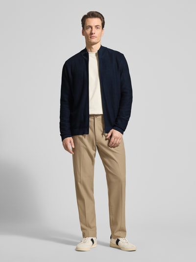 Męski model nosi Regular Fit Cardigan mit Stehkragen od OLYMP Level Five z bawełny, imitacja dzianiny, zamek błyskawiczny, elastyczne wykończenia, długość tyłu 68 cm, długość rękawa 67 cm, krój regular fit, widok całej sylwetki z przodu.