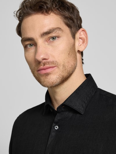 Männermodel trägt Slim Fit Business-Hemd aus Leinen mit Kentkragen von SEIDENSTICKER, schwarze Farbe, Knopfleiste, Nahaufnahme Oberkörper. Rückenlänge 69 cm, Schulterbreite 43 cm, Ärmellänge 64 cm bei Größe 40.