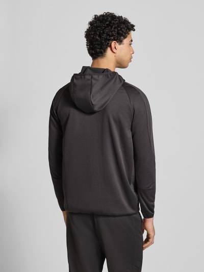Männermodel trägt Regular Fit Trainingsjacke mit Logo-Print von PUMA PERFORMANCE in Schwarz mit Kapuze und Reißverschluss, Ganzkörperansicht Rückansicht.