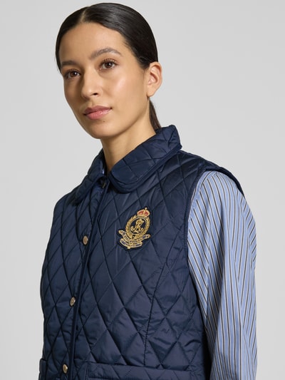 Kobiece modelka nosi Regular Fit Steppweste mit Umlegekragen od Lauren Ralph Lauren, kolor granatowy, pikowana, karo, naszyta kieszeń, metaliczne akcenty, logo-patch, krój regular fit, widok na górną część ciała z przodu.